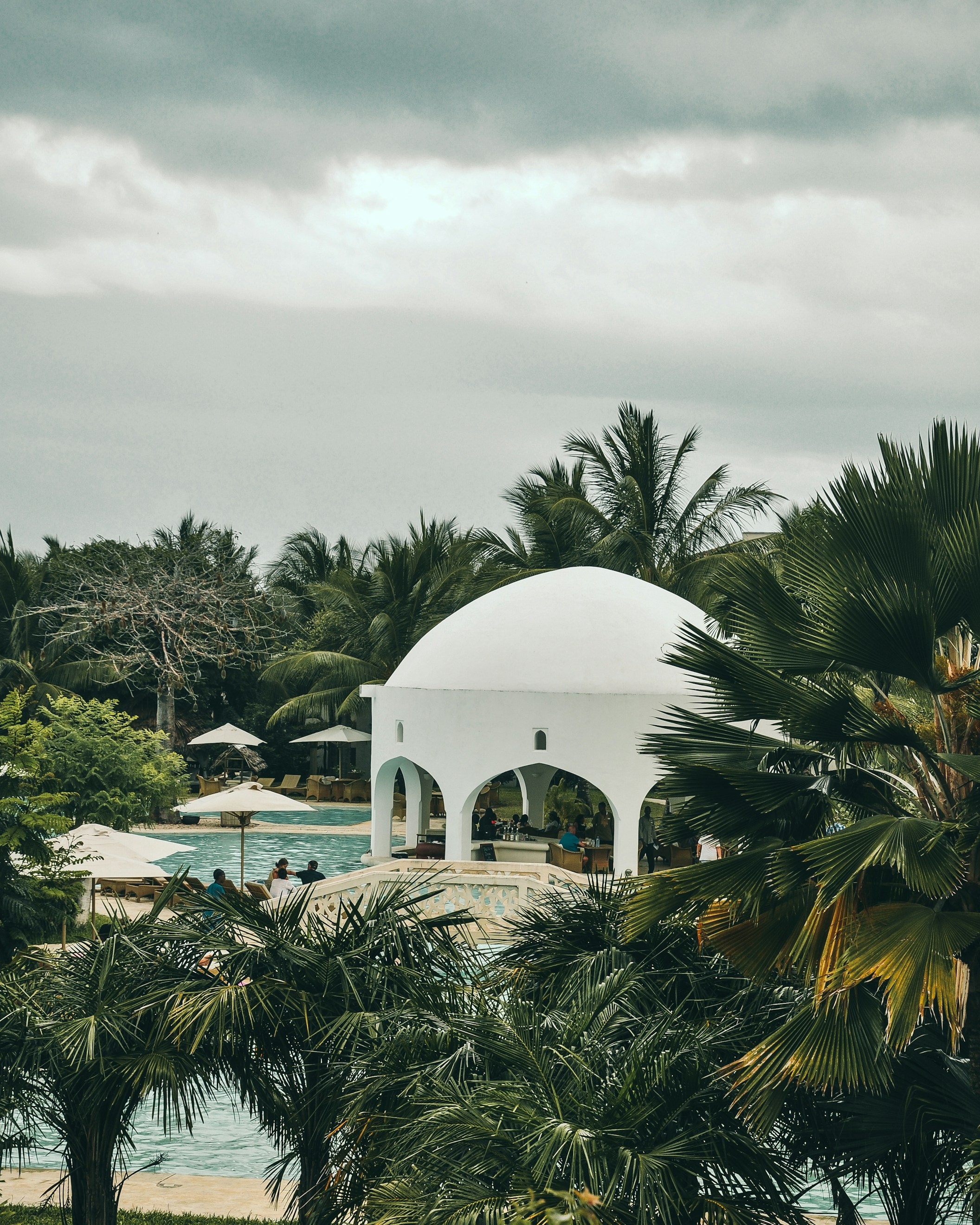 African resort with white domed structure and swimming pool surrounded by palm trees